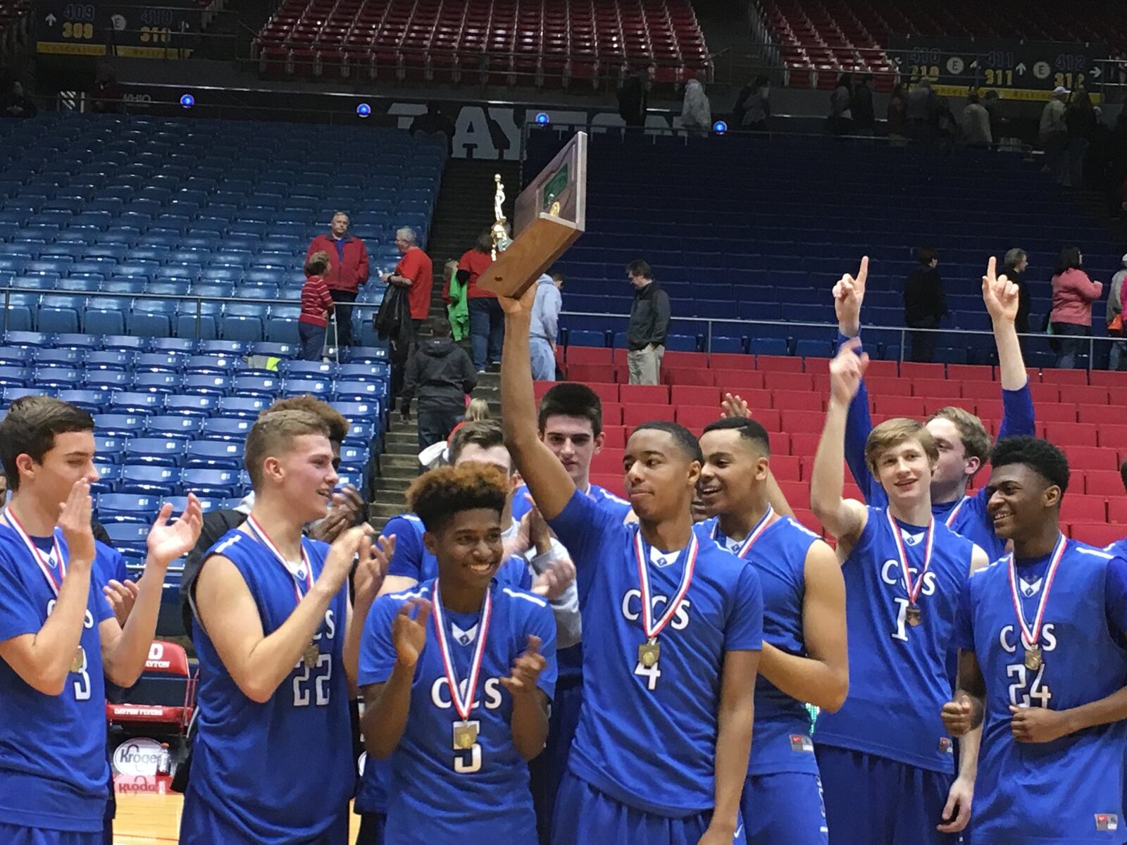 Cincinnati Christian’s Dylan Woods (4) holds up the Division IV district championship trophy Friday night after the Cougars defeated South Charleston Southeastern 54-52 at the University of Dayton Arena. RICK CASSANO/STAFF