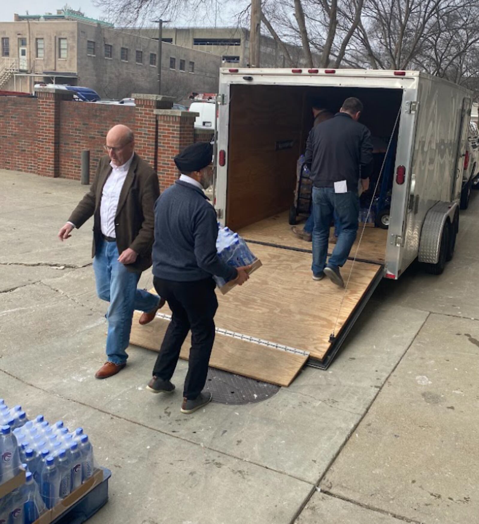 The city of Hamilton and Pahhni Water in Hamilton donated scores of cases in March to East Palestine, the Ohio village that was site of a train derailment that contaminated the water supply for the community. Pictured are Hamilton Mayor Pat Moeller, left, and Pahhni Water co-founder Satinder Bharaj, loading cases of water in March 2023. PROVIDED