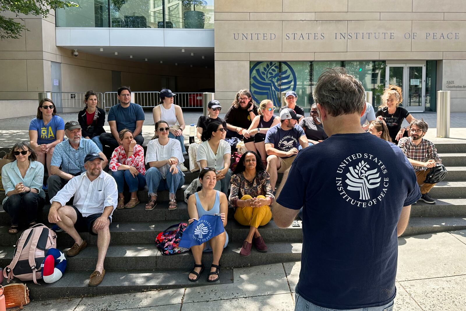U.S. Institute of Peace employees hold an impromptu celebration on the steps of the U.S. Institute of Peace, Monday, May 19, 2025, in Washington, after federal district Judge Beryl A. Howell blocked the Trump administration from moving forward with the dismantling the organization. (AP Photo/Gary Fields)