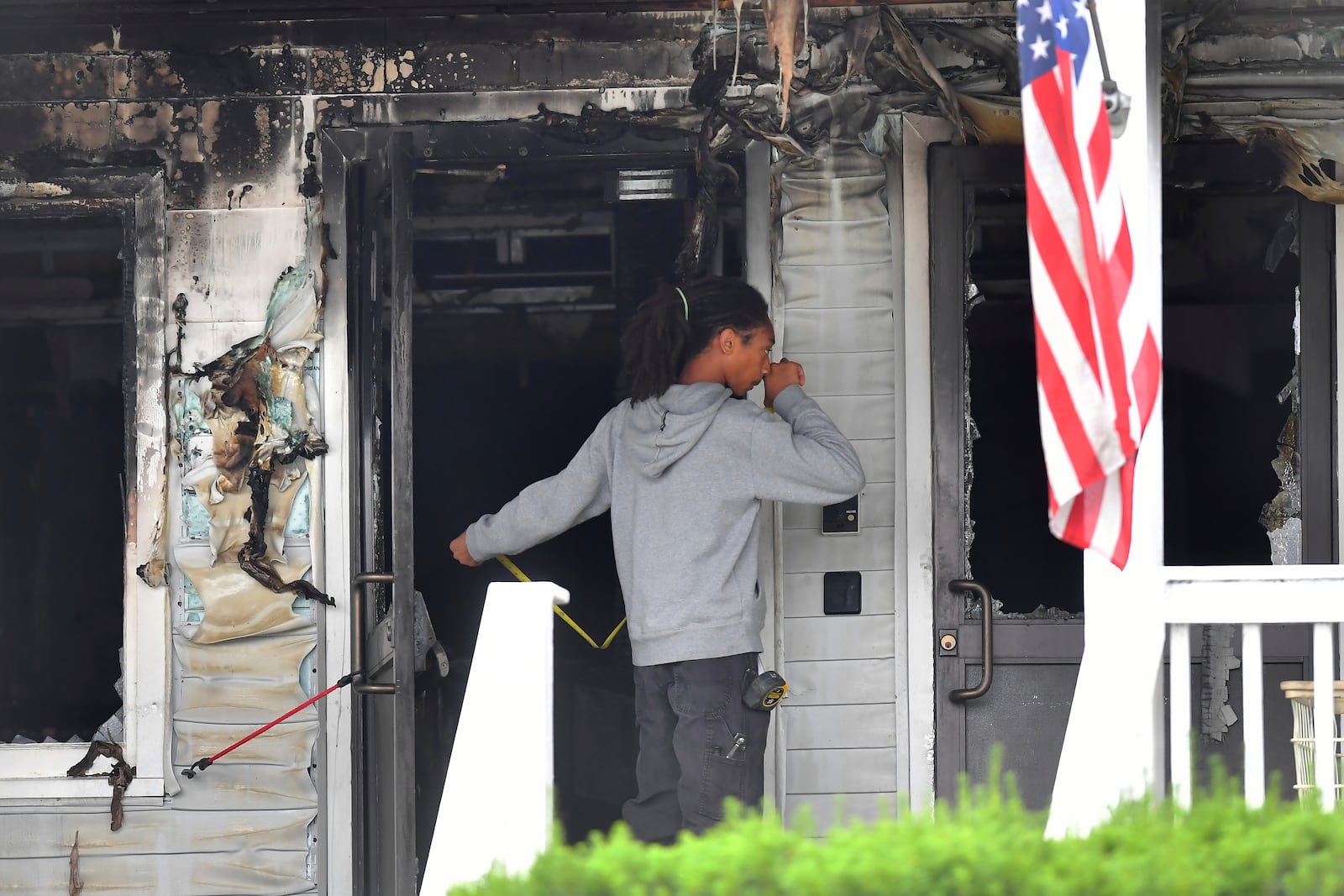 An investigator takes measurements Monday, July 14, 2025, near an entrance to the Gabriel House assisted living facility following a fire that started late Sunday, in Fall River, Mass. (AP Photo/Steven Senne)
