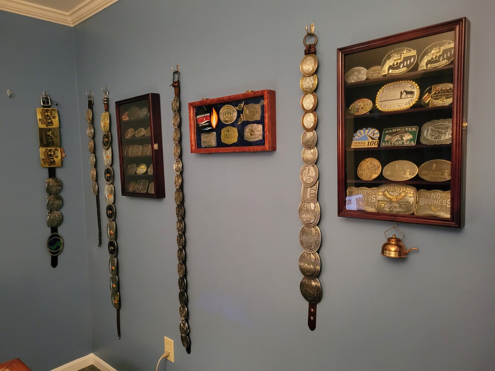 Dave Corfman's belt buckles - awarded to those who finish a 100-mile race - are displayed in his West Chester home. CONTRIBUTED PHOTO