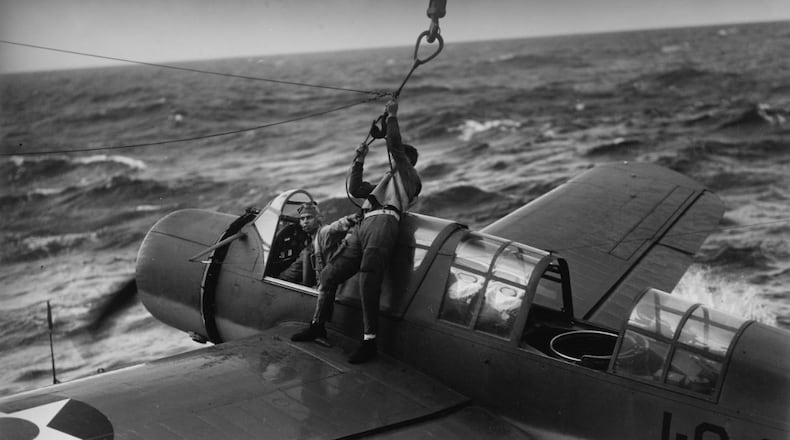 Pilot Ensign Lawrence A. Williams holds the belt of his rear-seat man, Radioman 3rd Class G.H. Lane, who is hooking up the aircraft to the USS Arizona’s crane for recovery. The date is Sept. 6, 1941 somewhere off the Hawaiian coast. The aircraft is a Vought OS2U Kingfisher floatplane, with ship’s name painted on the fuselage. CREDIT: NATIONAL ARCHIVES
