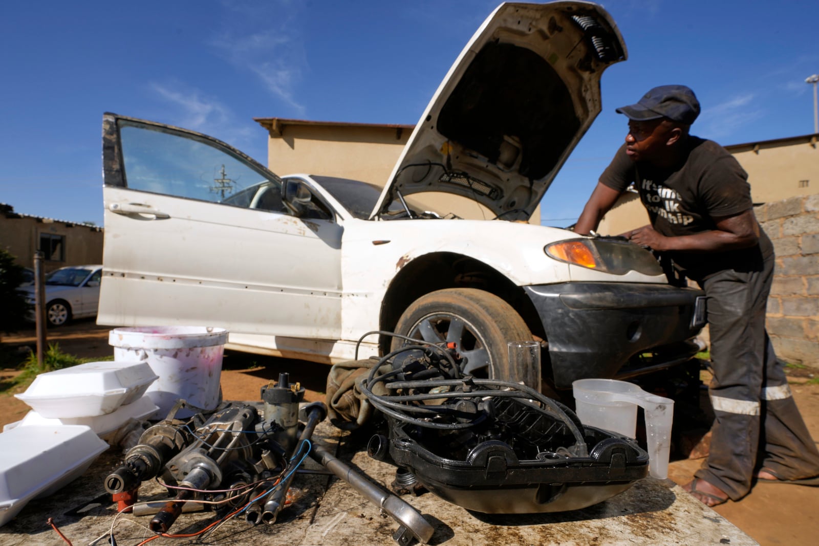 Themba Maseko, a 39-year-old mechanic, repairs a BMW car outside his workshop in Brakpan, east of Johannesburg, South Africa, Wednesday, May 14, 2025. (AP Photo/Themba Hadebe)