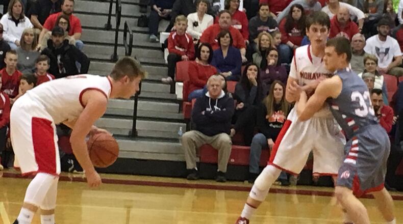 Madison’s Mason Whiteman prepares to run a play as teammate Grant Whisman is guarded by Carlisle’s Dane Flatter (33) during a game Jan. 23, 2018, in Madison Township. The host Mohawks won 60-41. RICK CASSANO/STAFF