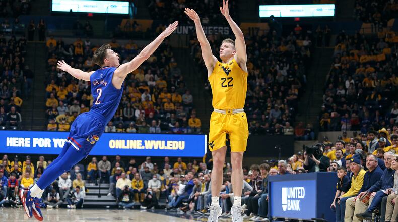 West Virginia guard Sean McNeil (22) shoots over Kansas guard Christian Braun (2) during the second half of an NCAA college basketball game in Morgantown, W.Va., Saturday, Feb. 19, 2022. (AP Photo/Kathleen Batten)