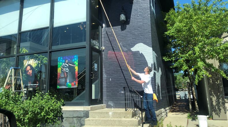 A worker cleans the outside of a Brown Street business earlier this month. CORNELIUS FROLIK / STAFF