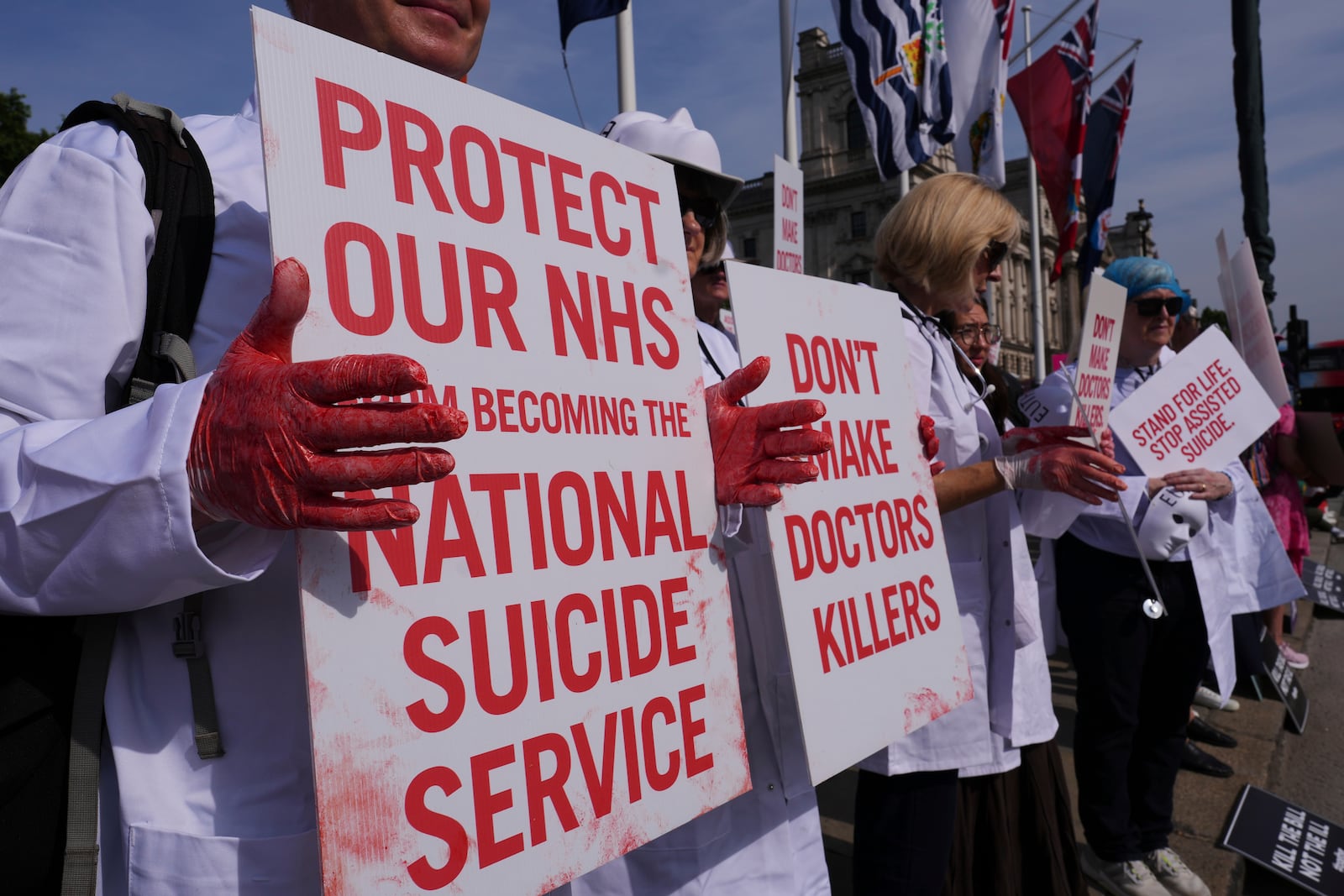 Demonstrators against assisted dying hold banners outside Parliament in London, Friday, June 20, 2025, as British lawmakers are set to vote Friday on whether to back a bill to help terminally ill adults end their lives in England and Wales. (AP Photo/Kirsty Wigglesworth)