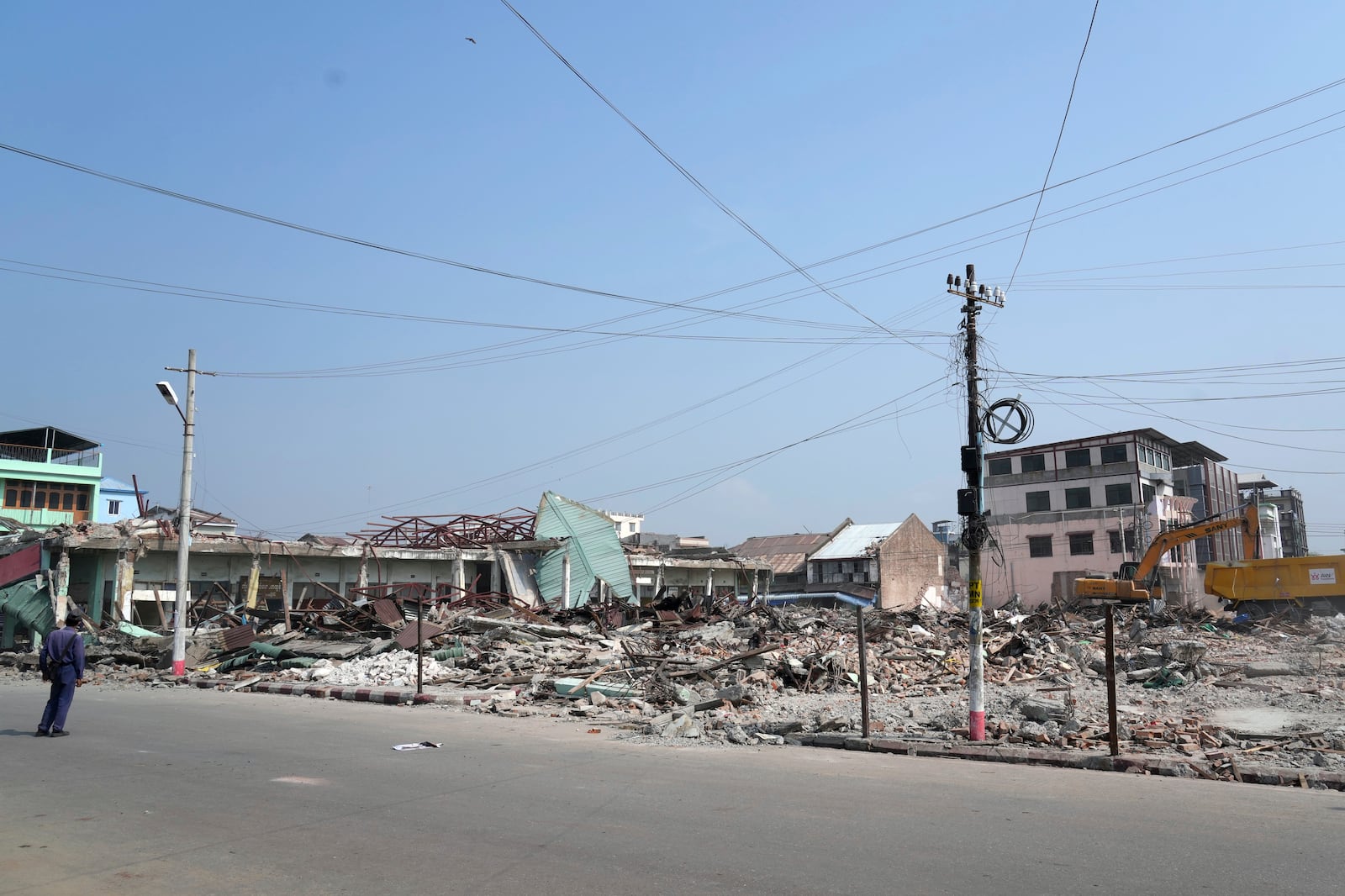 A volunteer drives a backhoe to clear debris of a building at a market, after one month of the strong earthquake in Naypyitaw, Myanmar, Monday, April 28, 2025. (AP Photo/Aung Shine Oo)