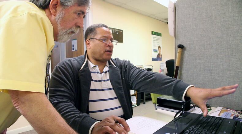 Affordable Care Act Navigator Ron Irvine, left, helps Dayton resident Kenneth Flowers, 56, get reconnected to the government website after Flowers got disconnected on Monday, the deadline for signing up for government healthcare TY GREENLEES / STAFF