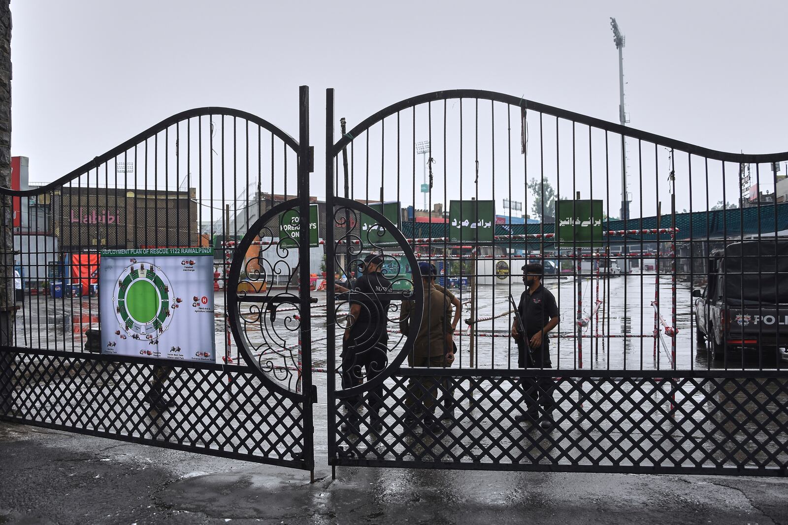 Police officers stand guard behind a closed gate of an entry point to Pindi Cricket Stadium following a suspected Indian drones crashed in the parking area, in Rawalpindi, Pakistan, Thursday, May 8, 2025. (AP Photo/W.K. Youszai)