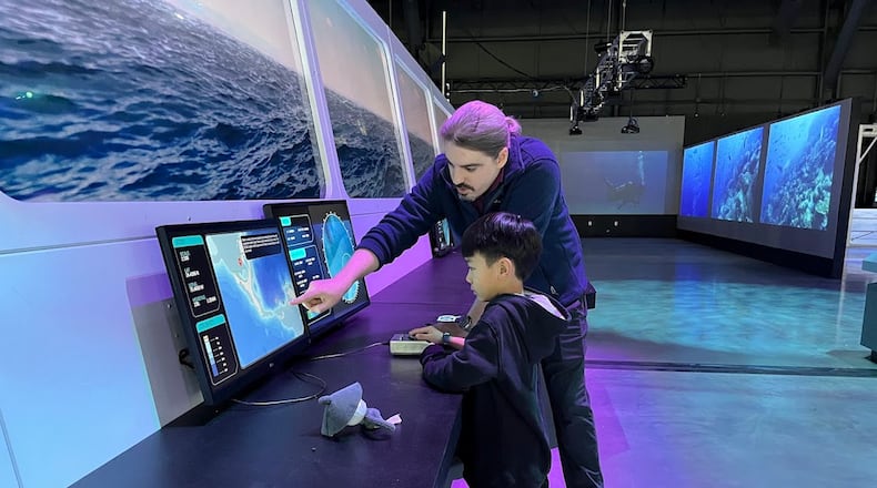Bill Horner, attractions manager for the Air Force Museum Foundation, shows a young guest Tuesday Feb. 4, 2025 part of the museum's new (but temporary) OceanXperience exhibit. THOMAS GNAU/STAFF