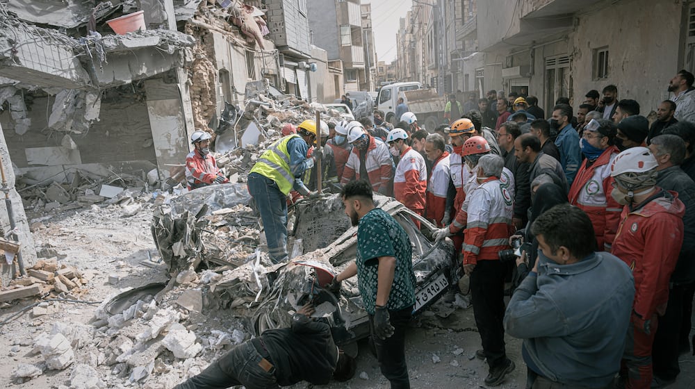 First responders inspect a destroyed car at the site of a residential building hit in an overnight strike during the U.S.-Israeli military campaign in Tabriz, East Azerbaijan Province, northwestern Iran, Tuesday, March 24, 2026. (AP Photo/Matin Hashemi)