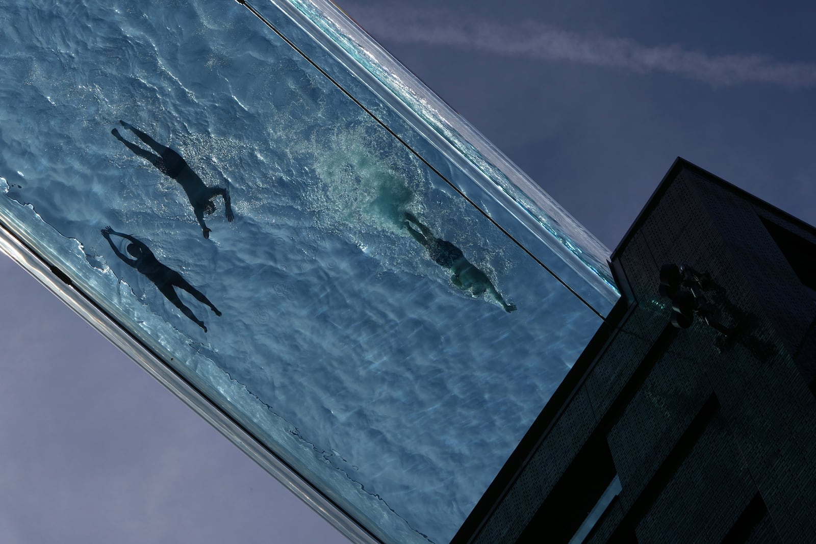 People swim in the Sky Pool on a sunny day in London, Thursday, May 1, 2025. (AP Photo/Kin Cheung)