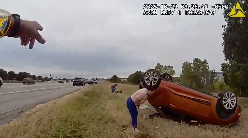This image taken from video released by the Fort Worth Police Department shows officers responding to an overturned car before pulling a baby out from underneath Thursday, Oct. 23, 2025, in Fort Worth, Texas. (Fort Worth Police Department via AP)