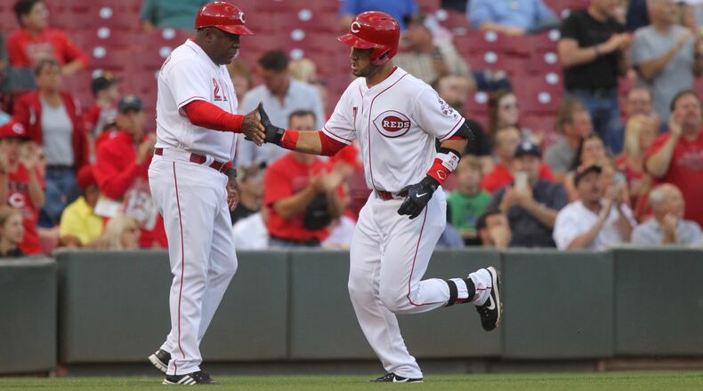 The Reds’ Eugenio Suarez, right, slaps hands with third-base coach Billy Hatcher after a home run against the Brewers on Tuesday, June 27, 2017, at Great American Ball Park in Cincinnati.