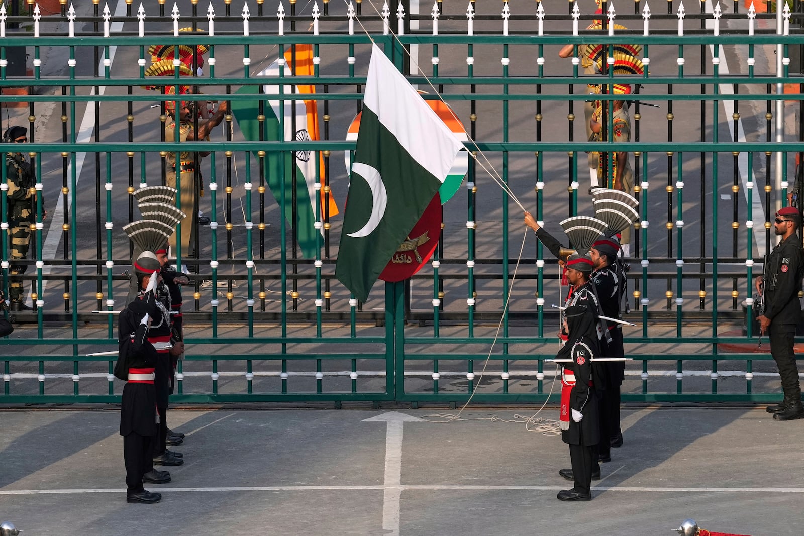 Pakistan's Rangers soldiers, in black, and Indian Border Security Forces soldiers, behind the gate, lower their flags during a daily closing ceremony at the Wagah, a joint post on the Pakistan and India border, near Lahore, Pakistan, Monday, May 5, 2025. (AP Photo/K.M. Chaudary)