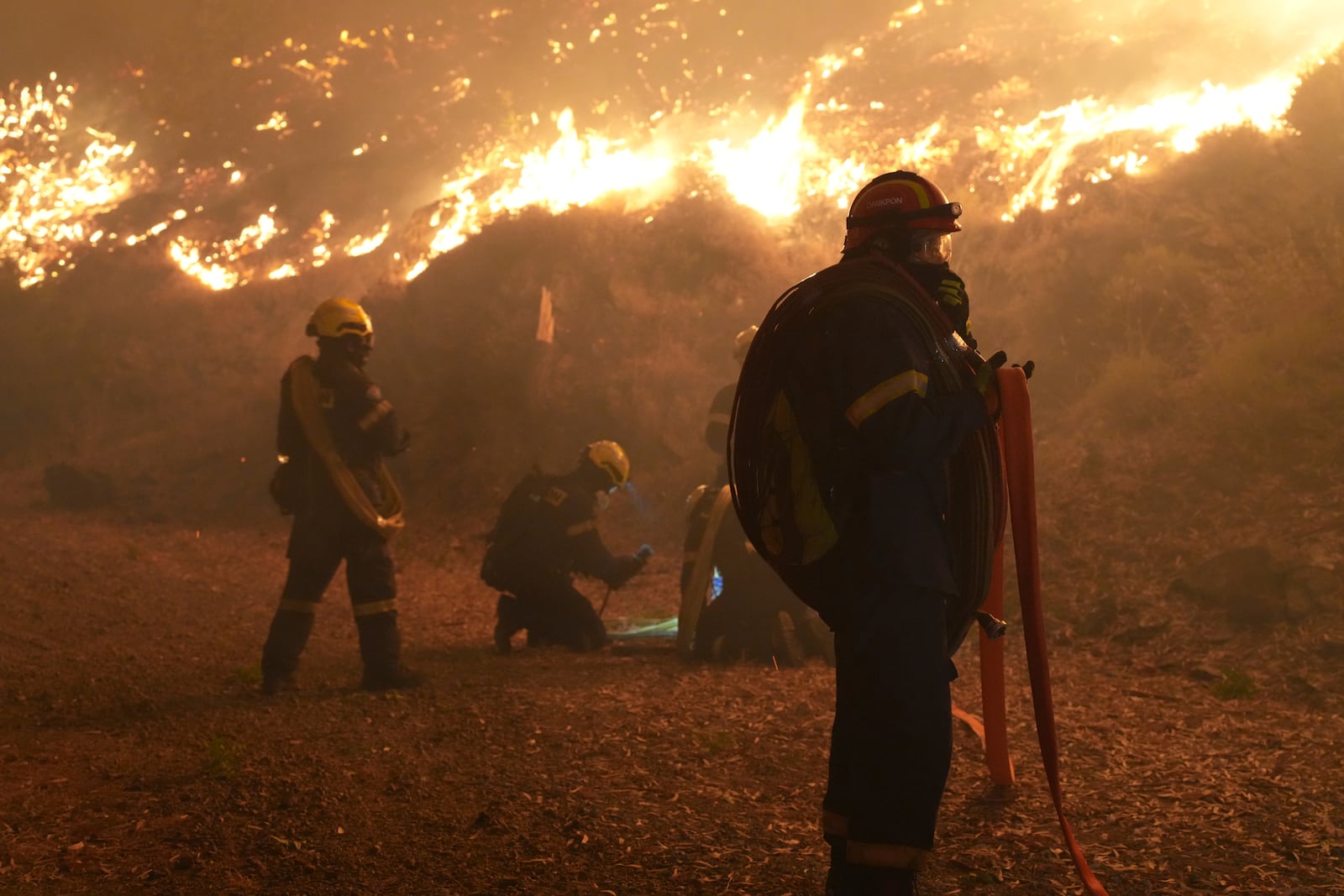 Firefighters battle with a wildfire burning in Kofinas, on the eastern Aegean island of Chios, Greece, late Sunday, June 22, 2025. (Pantelis Fykaris/Politischios.gr via AP)