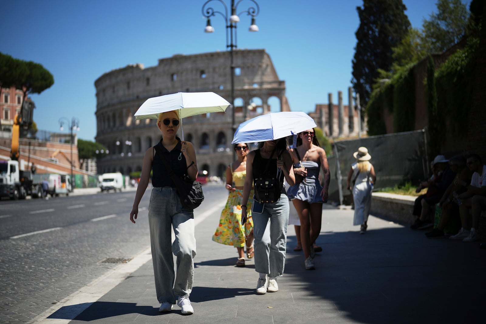People use umbrellas in hot weather to shelter from the sun while walking past the Colosseum, in Rome, Monday, June 30, 2025. (AP Photo/Andrew Medichini)