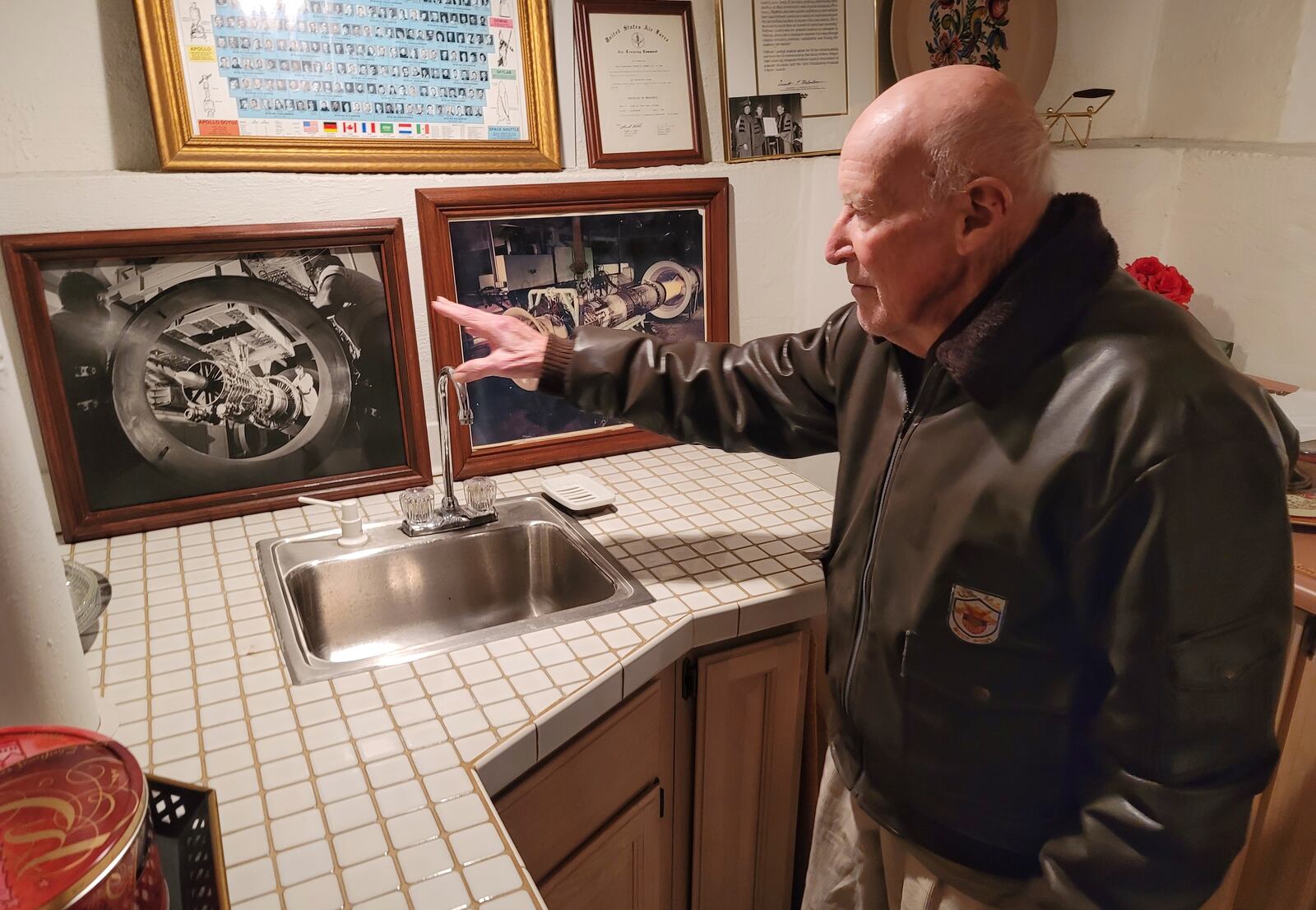 Barney Landry shows off pictures at his Hamilton home of jet engines he helped design while working at General Electric. Landry graduated from West Point and was a pilot in the Air Force who flew into radioactive clouds to collect data during nuclear testing in Marshall Islands. He then became an engineer at General Electric. NICK GRAHAM / STAFF