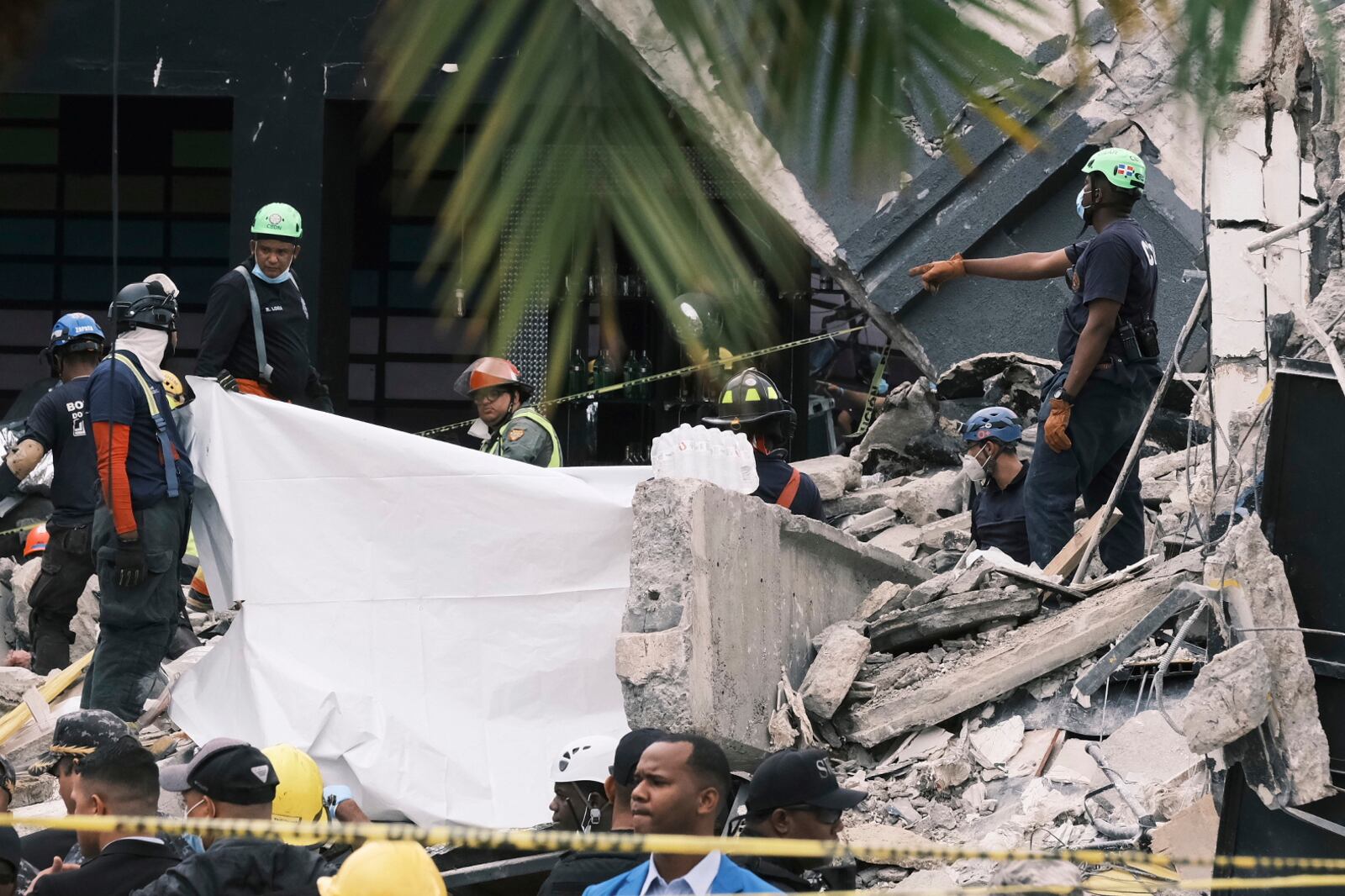 Rescue workers use sheets as they recover bodies from the rubble at the Jet Set nightclub after its roof collapsed two nights prior during a merengue concert in Santo Domingo, Dominican Republic, Wednesday, April 9, 2025. (AP Photo/Ricardo Hernandez)