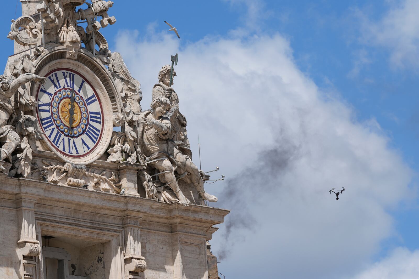 A drone flies as black smoke billows from the chimney of the Sistine Chapel where 133 cardinals are gathering on the second day of the conclave to elect a successor to late Pope Francis, at the Vatican, Thursday, May 8, 2025. (AP Photo/Luca Bruno)