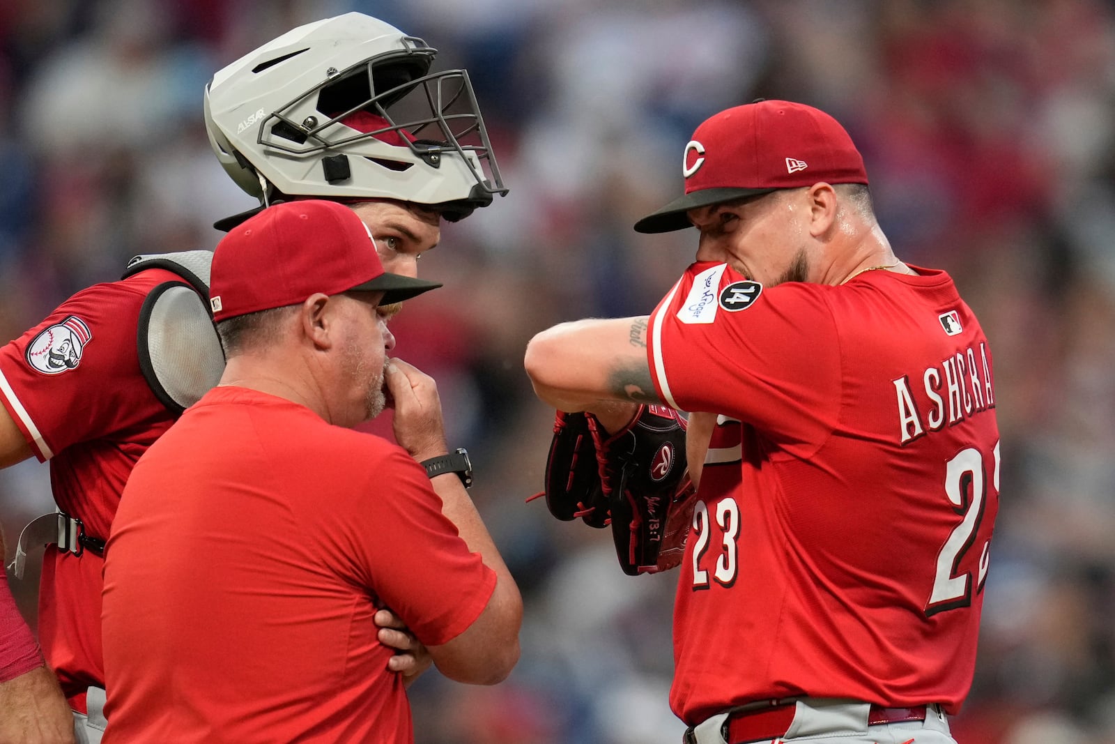 Cincinnati Reds relief pitcher Graham Ashcraft (23) talks with catcher Tyler Stephenson, center, and pitching coach Derek Johnson, left, in the seventh inning of a baseball game against the Cleveland Guardians in Cleveland, Monday, June 9, 2025. (AP Photo/Sue Ogrocki)