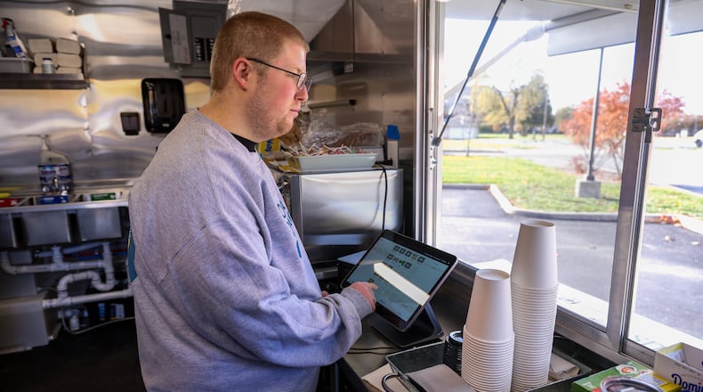 Nathan Prouty rings purchases at the Good Connections food truck on Wednesday, Nov. 12. Prouty is one of the employees of the Goodwill Easterseals Miami Valley program that teaches job skills to individuals with developmental disabilities. BRYANT BILLING/STAFF