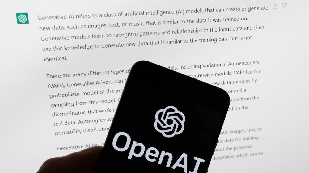 FILE - The OpenAI logo is displayed on a mobile phone in front of a computer screen with output from ChatGPT, March 21, 2023, in Boston. (AP Photo/Michael Dwyer, File)