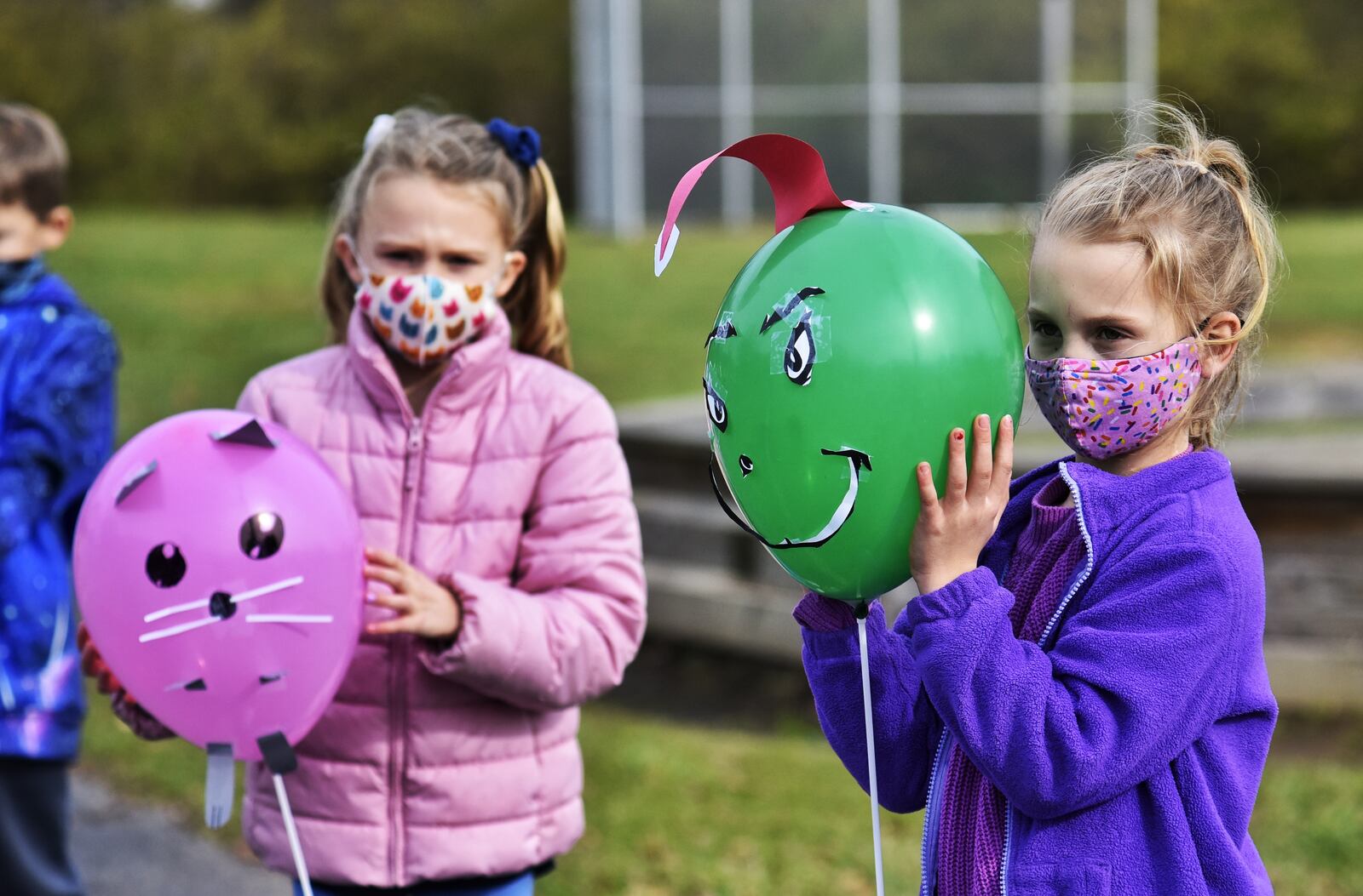 Kaylin Justice, holding her Grinch balloon, right, Amelia Hussel, left, and other second graders at Fairfield South Elementary School decorated balloons for a parade outside for other students Tuesday, Nov. 24, 2020 on Bibury Road in Fairfield. NICK GRAHAM/ STAFF