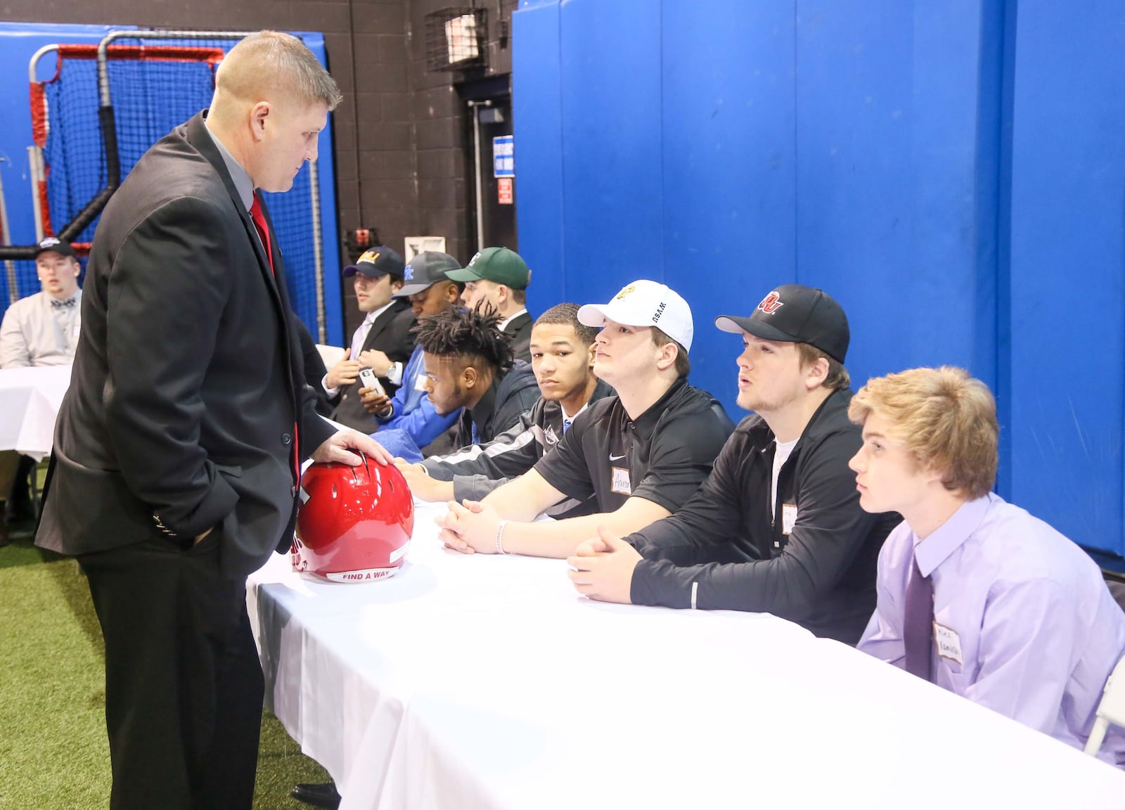 Fairfield football coach Jason Krause talks to his players (James Mitchell, Ethan Burch, Aaron McKenzie, Jerred McGuire and Alex Kaminsky) during the National Signing Day event hosted by the Greater Miami Conference football coaches at Beacon Orthopaedics and Sports Medicine in Sharonville on Wednesday. GREG LYNCH/STAFF