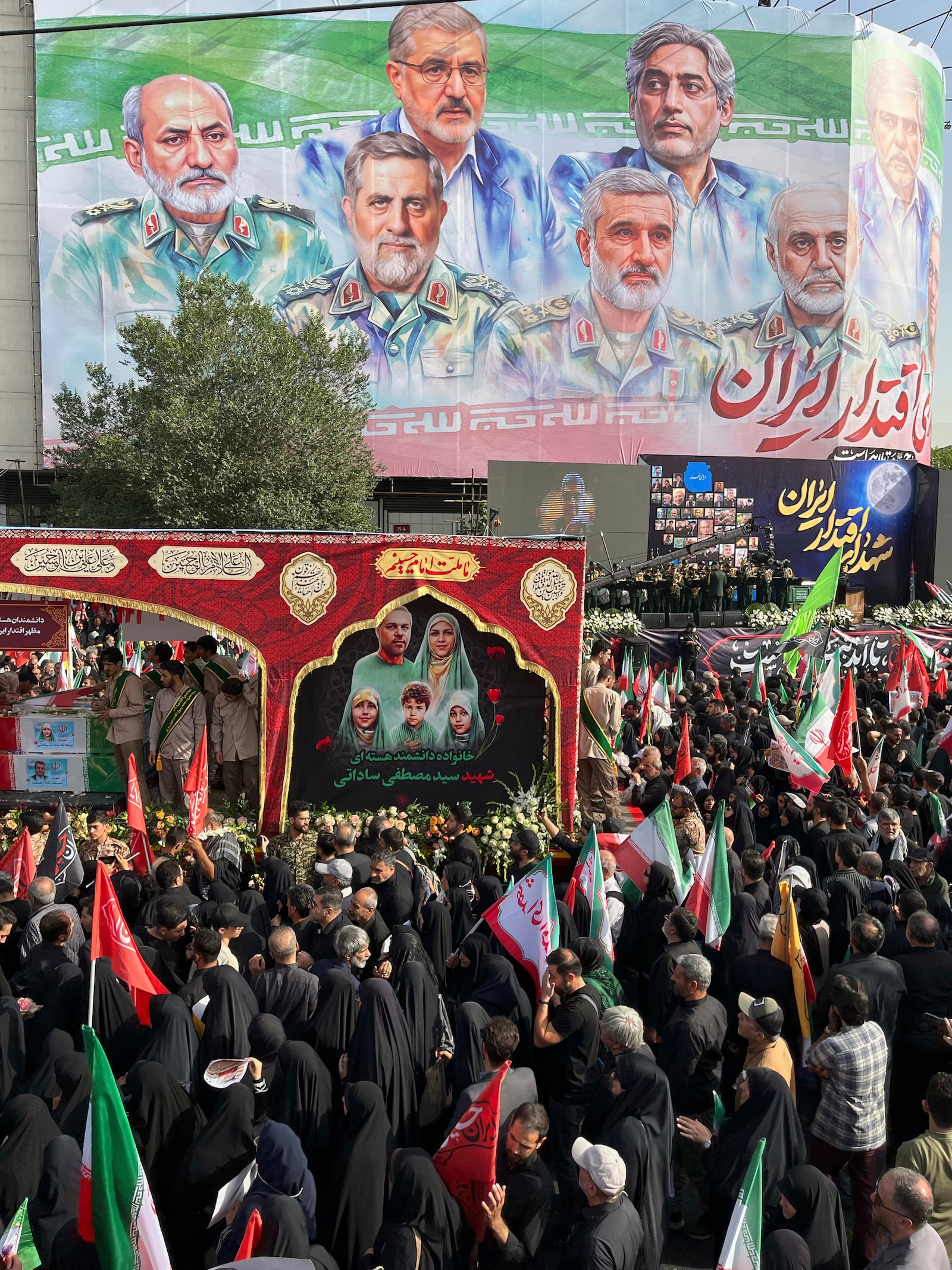 People mourn over the flag-draped coffins of Iranian army generals, nuclear scientists and their family members who were killed in Israeli strikes, during a funeral ceremony in Tehran. Iran, Saturday, June 28, 2025. (AP Photo/Vahid Salemi)