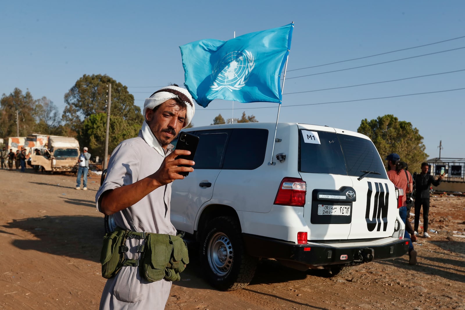 A Bedouin fighter takes a selfie in front of a U.N. vehicle as a convoy of ambulances and buses arrives at a checkpoint in the village of Busra al-Harir, southern Syria, on its way to Sweida province, as security forces cordon off the area to block Bedouin fighters from entering the province, Tuesday, July 22, 2025. (AP Photo/Omar Sanadiki)