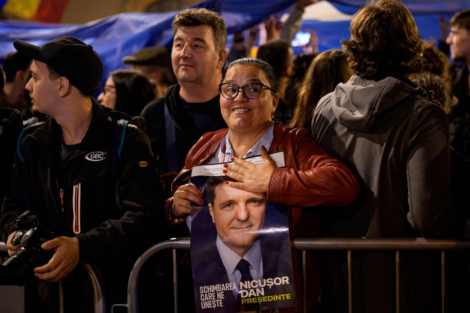 A supporter of presidential candidate Nicusor Dan holds an electoral poster after he won the second round of the country's presidential election redo in Bucharest, Romania, early Monday, May 19, 2025. (AP Photo/Andreea Alexandru)