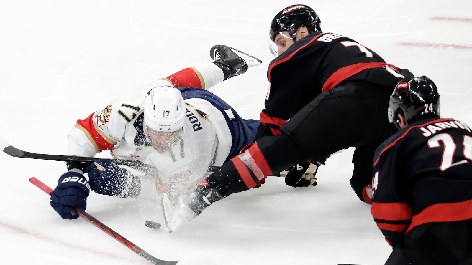 Florida Panthers center Evan Rodrigues (17) and Carolina Hurricanes defenseman Dmitry Orlov (7) battle for the puck during the third period of Game 5 of the NHL hockey Stanley Cup Eastern Conference finals Wednesday, May 28, 2025, in Raleigh, N.C. (AP Photo/Chris Seward)