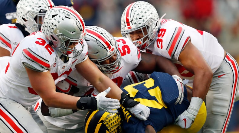 FILE - Ohio State linebackers Tuf Borland (32), Davon Hamilton (53) and Malik Harrison (39) smother Michigan running back Hassan Haskins (25) in the second half of an NCAA college football game in Ann Arbor, Mich., in this Saturday, Nov. 30, 2019, file photo. Michigan canceled its annual rivalry game at Ohio State on Tuesday, Dec. 8, 2020, because of the COVID-19 outbreak within the Wolverines football program. (AP Photo/Paul Sancya, File)