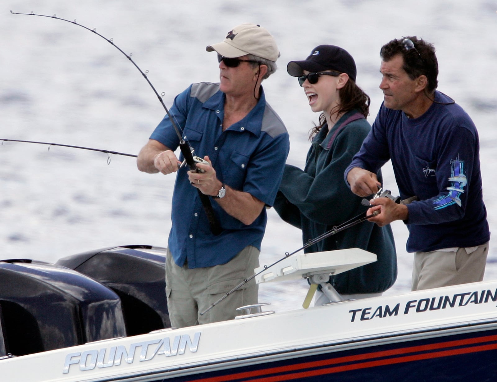 FILE - President George W. Bush, from left, reels in his catch as his daughter Barbara Bush and fishing guide BIlly Bush look on, June 30, 2007, in Kennebunkport, Maine. (AP Photo/Robert F. Bukaty, File)