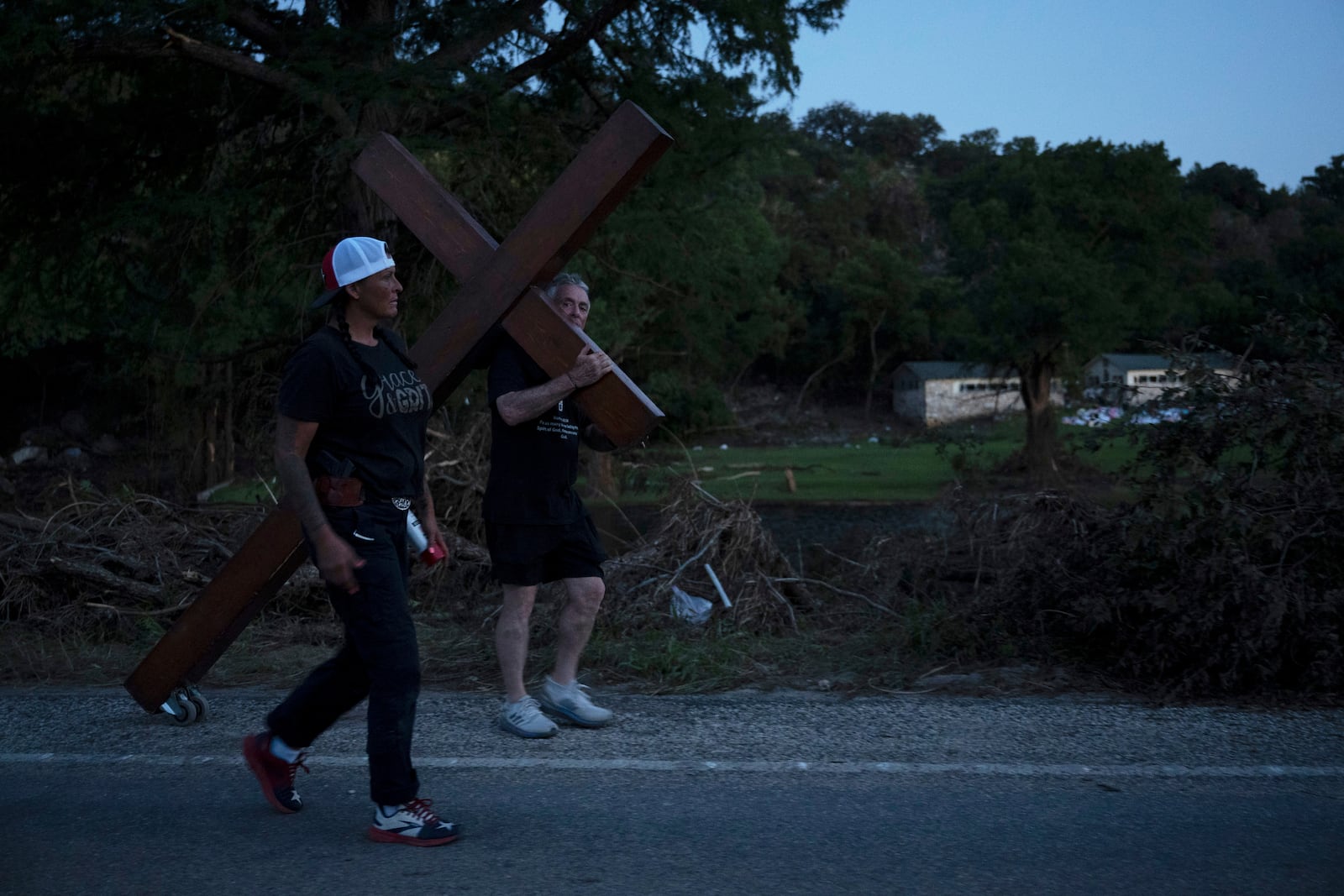 Disaster relief chaplain Sandi Gilmer, left, and Dan Beazley search for a permanent place for Beazley's large cross in memory of flooding victims on Tuesday, July 8, 2025, near Camp Mystic in Hunt, Texas, after a flash flood swept through the area. (AP Photo/Eli Hartman)
