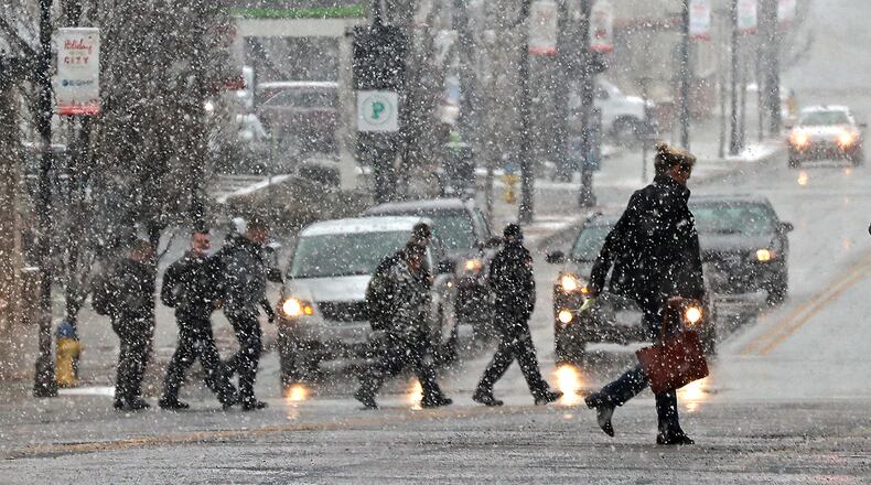 Pedestrians are silhouetted as they cross Fountain Avenue during a snow shower recently. BILL LACKEY/STAFF