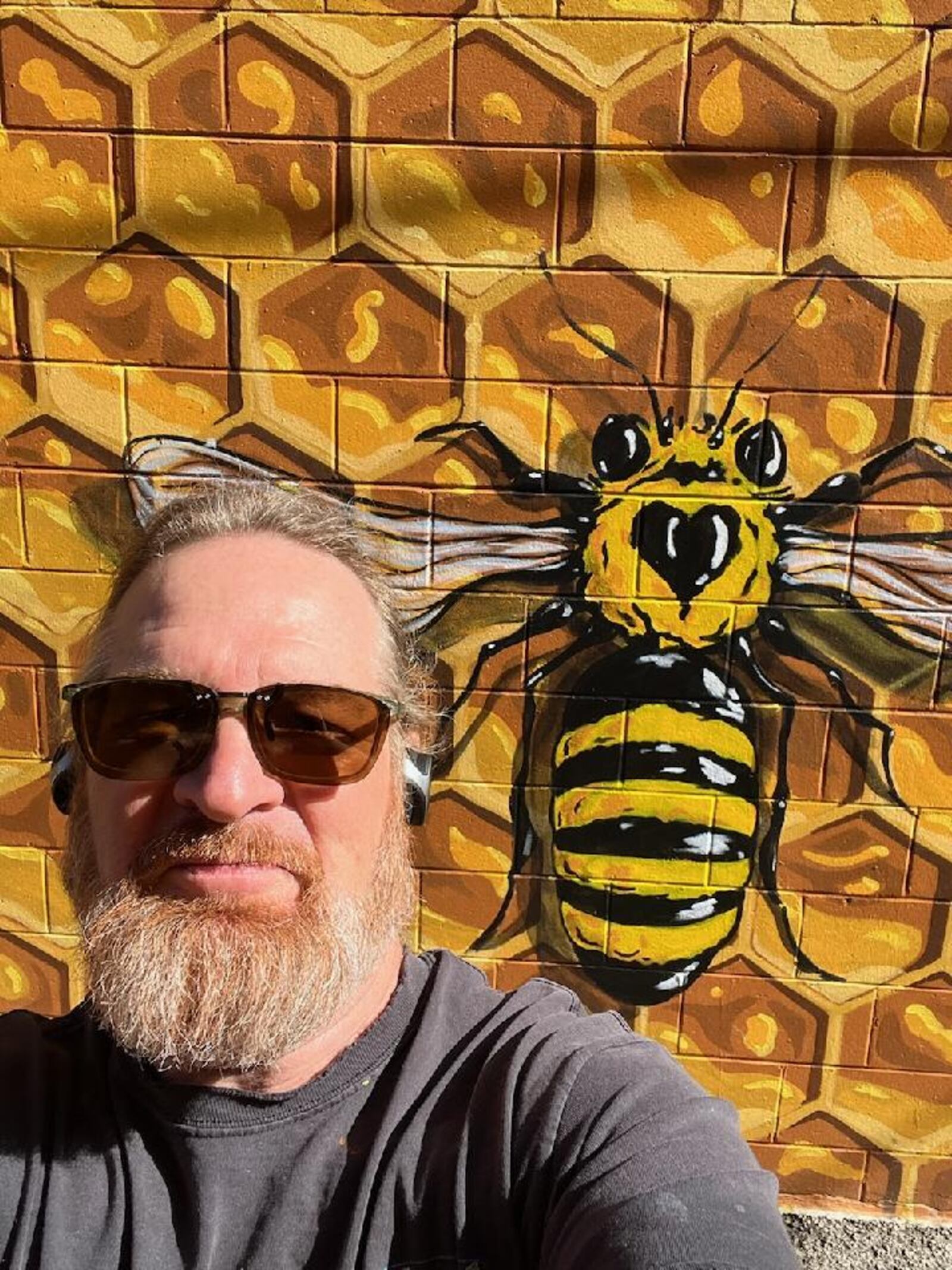 Artist Joe Prescher takes a selfie in front of the Oxford "Hive" mural, which is located off High Street in Uptown Oxford.