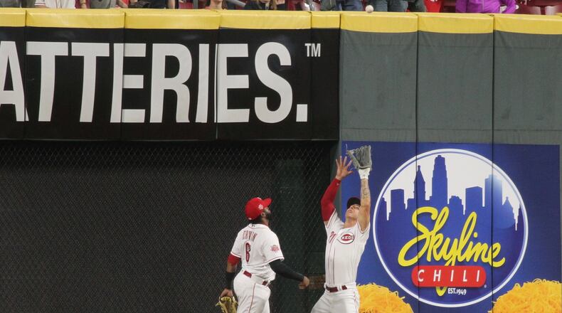 Reds center fielder Michael Lorenzen makes a catch against the wall in the ninth inning as left fielder Phillip Ervin watches during a game against the Braves on Tuesday, April 23, 2019, at Great American Ball Park in Cincinnati. David Jablonski/Staff