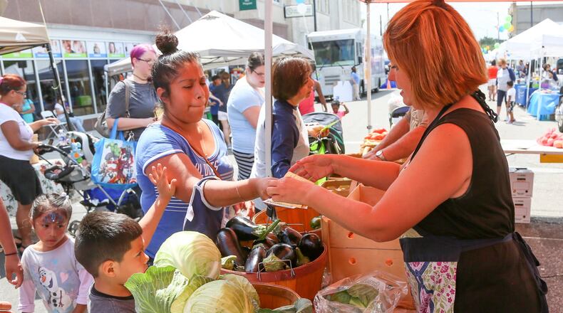Butler County WIC and Primary Health Solutions hosted a block party on Second Street, Tuesday, Aug. 15, 2017, to celebrate WIC’s Farmers Market Nutrition Program. Suzanne Garver of Garver Family Farms helps customers pick out produce during the event. GREG LYNCH / STAFF