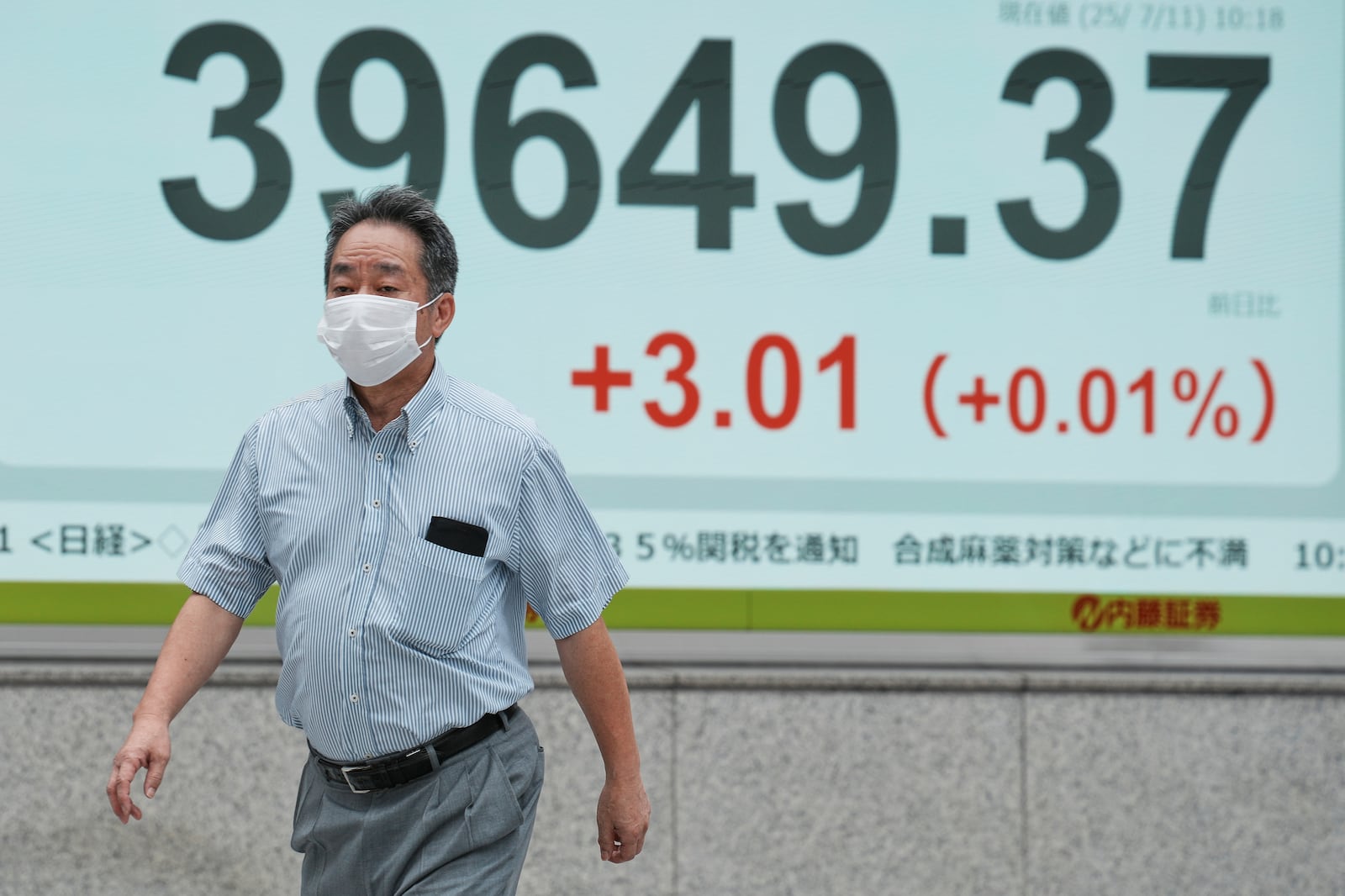 A person walks in front of an electronic stock board showing Japan's Nikkei index at a securities firm Friday, July 11, 2025, in Tokyo. (AP Photo/Eugene Hoshiko)