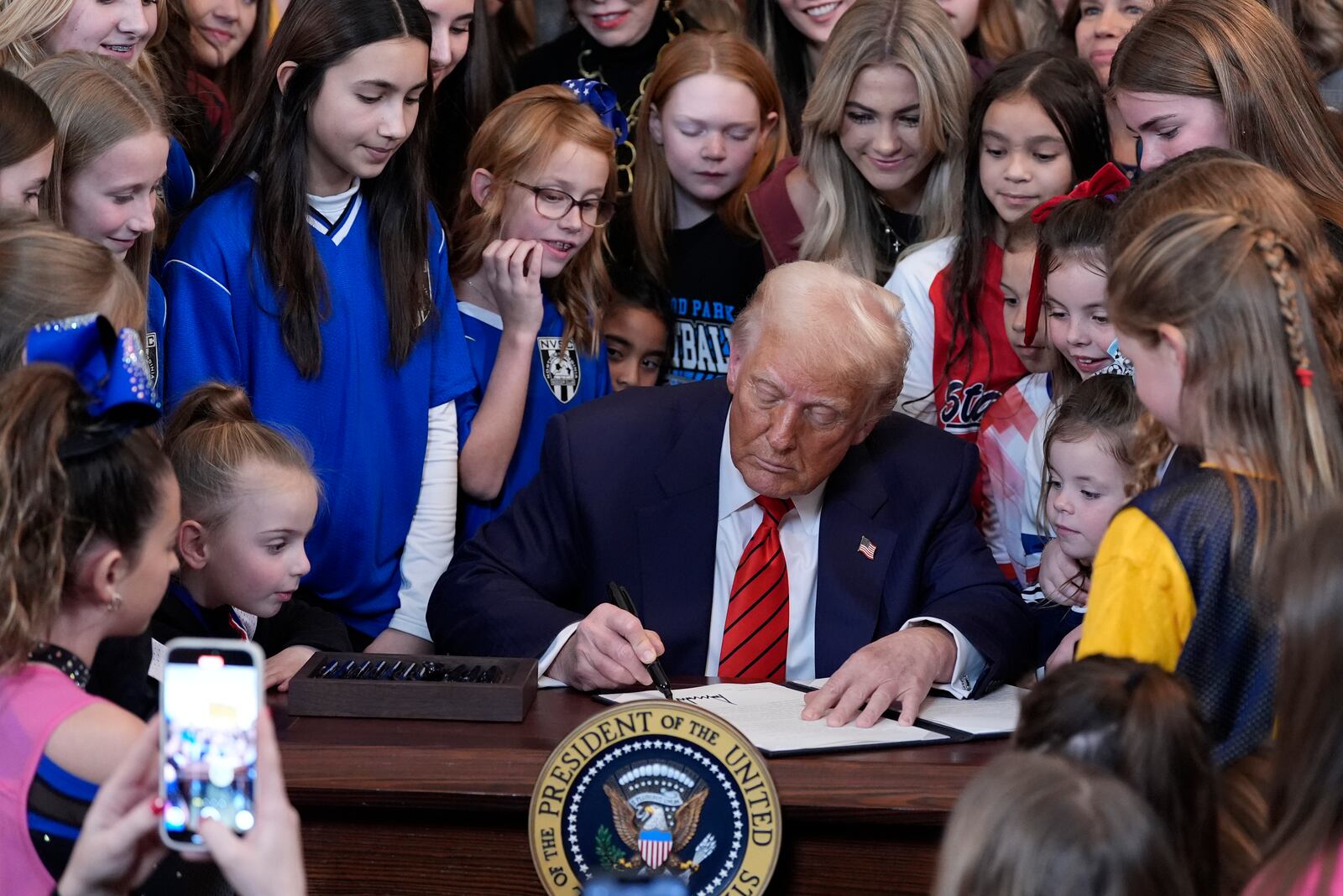 FILE - President Donald Trump signs an executive order barring transgender female athletes from competing in women's or girls' sporting events, in the East Room of the White House, in Washington, Feb. 5, 2025. (AP Photo/Alex Brandon, FIle)