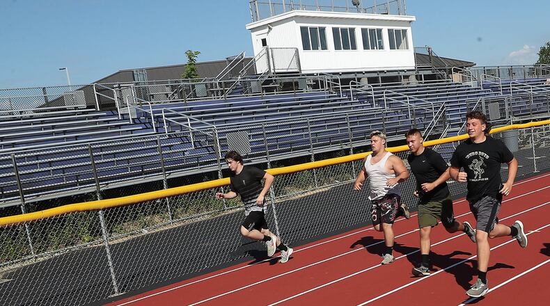 Senior football players at Mechanicsburg High School run past the empty bleachers at the school’s stadium Thursday. With the Coronavirus pandemic, its not clear if fans will be in the stands for games this season. BILL LACKEY/STAFF