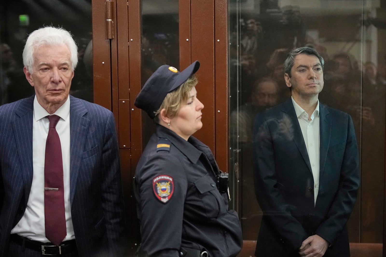 Grigory Melkonyants, right, co-chair of Russia's leading independent election monitoring group Golos who faces up to 5 years in prison, looks at the media standing in a cage in a courtroom prior to a hearing as Lawyer Mikhail Biryukov, stands near in Basmanny district court in Moscow, Russia, Wednesday, May 14, 2025. (AP Photo/Alexander Zemlianichenko)