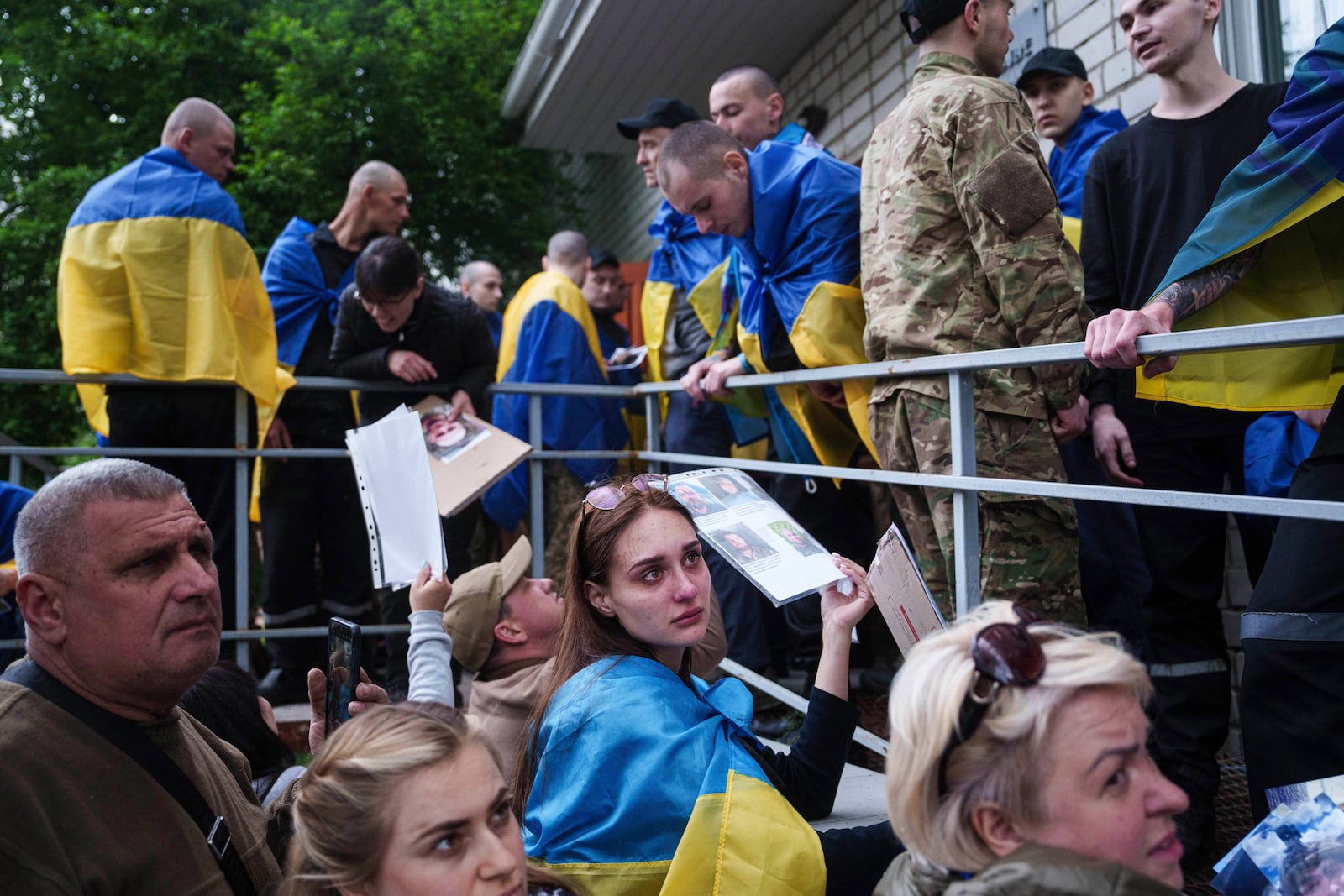 FILE - Relatives of missing and imprisoned Ukrainian soldiers show photographs to servicemen returning from captivity in a POW exchange in Ukraine, Tuesday, May 6, 2025. (AP Photo/Evgeniy Maloletka, File)