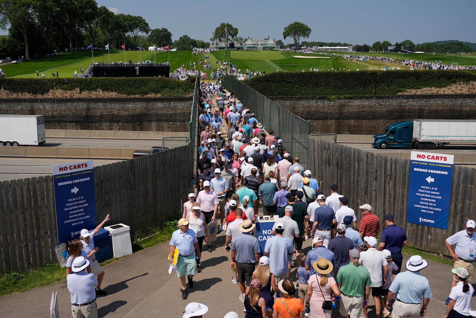 Fans use a pedestrian bridge over the Pennsylvania Turnpike, which divides Oakmont Country Club, during a practice round ahead of the U.S. Open golf tournament Wednesday, June 11, 2025, in Oakmont, Pa. (AP Photo/Carolyn Kaster)