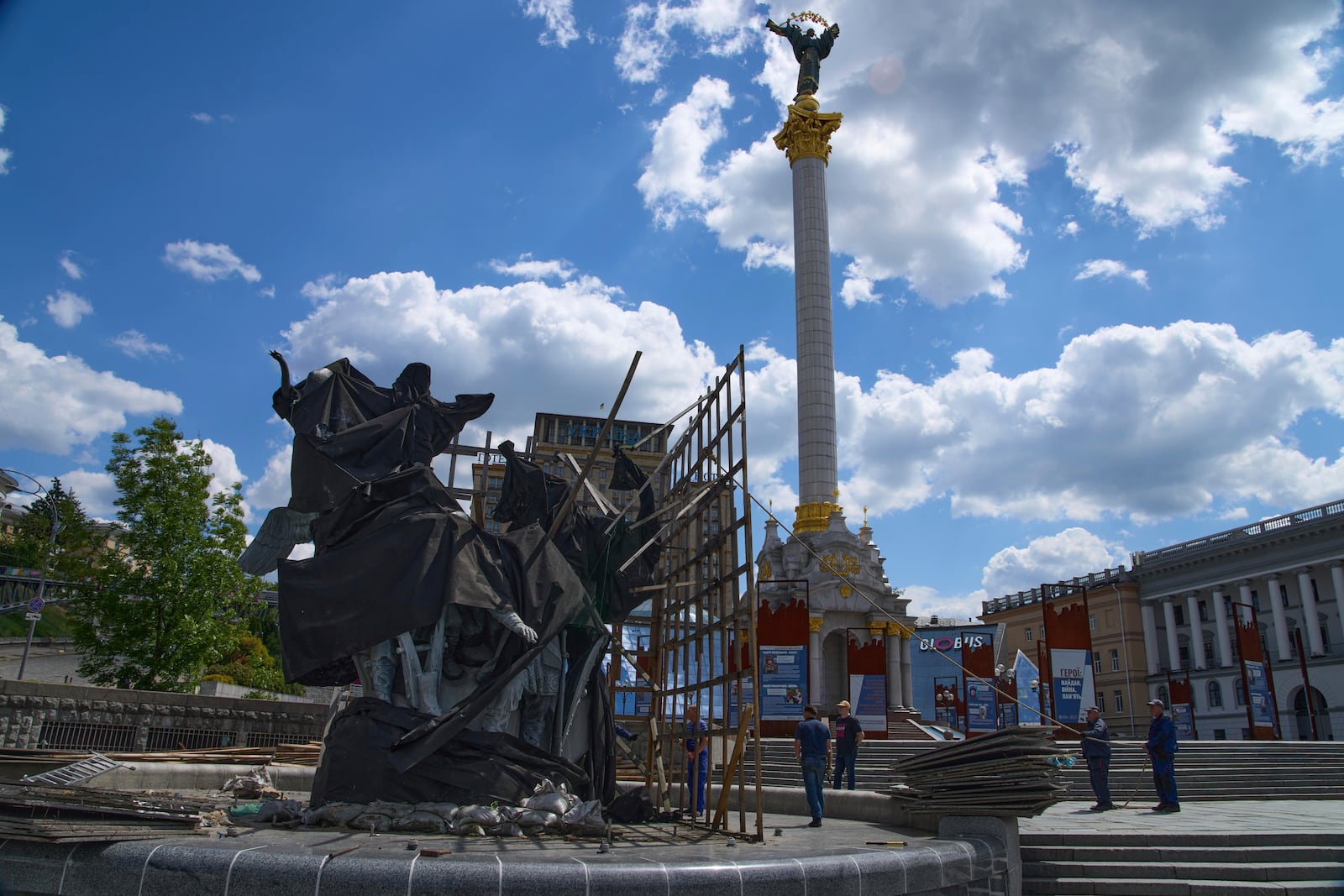 Municipal workers remove the cover that protected a monument of Kyiv legendary founders from Russian missile attacks on the fourth year of Russia-Ukraine war on the country's main square in Kyiv, Ukraine, Wednesday, May 21, 2025. (AP Photo/Efrem Lukatsky)(