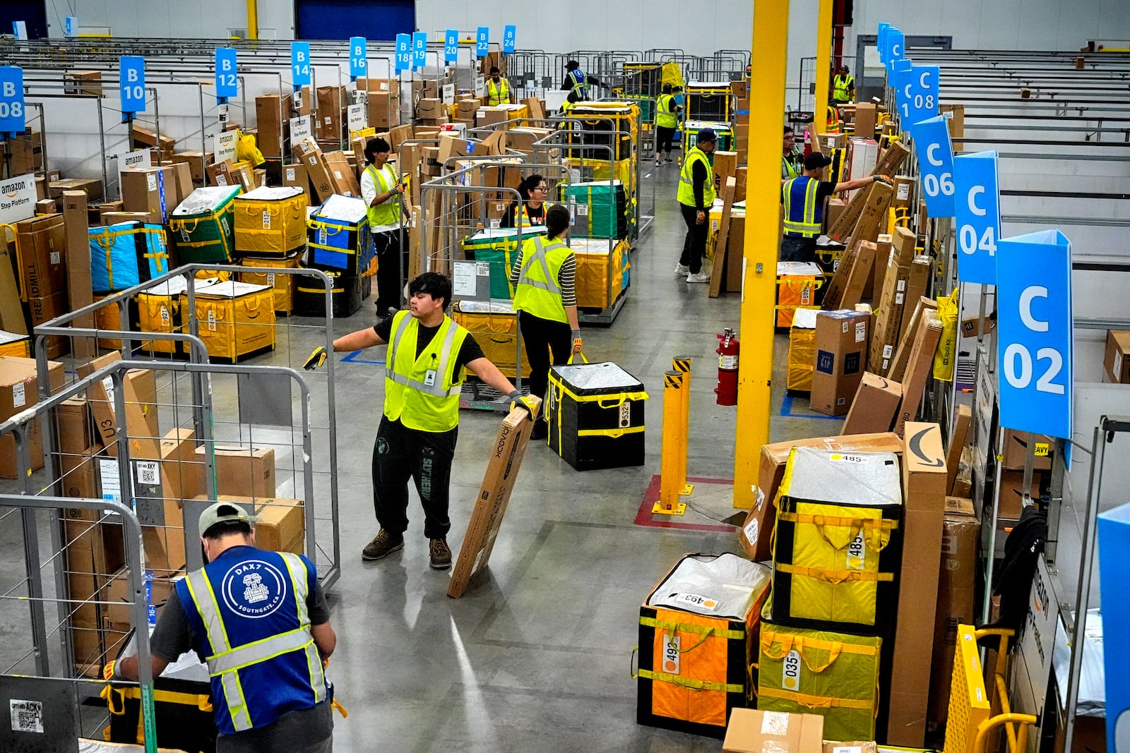 FILE - Amazon employees load packages on carts before being put on to trucks for distribution for Amazon's annual Prime Day event at an Amazon's DAX7 delivery station, July 16, 2024, in South Gate, Calif. (AP Photo/Richard Vogel, File)