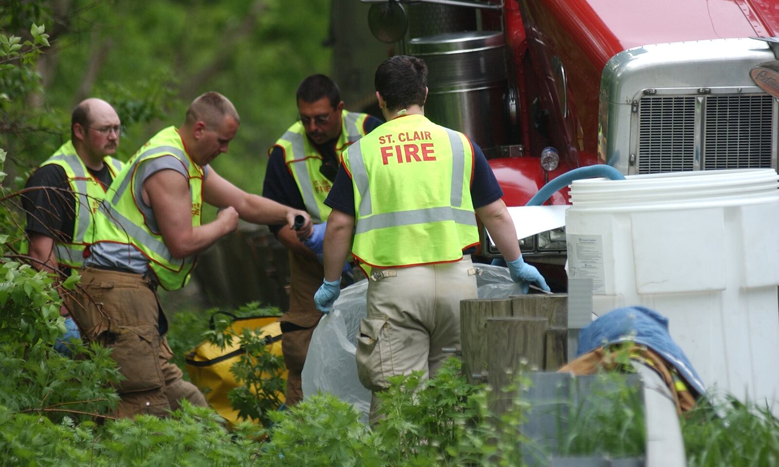 Members of the St. Clair Twp. Fire Department work to pump out the remaining dozens of gallons of diesel fuel that spilled from a semi after it was struck by a southbound car Tuesday morning, April 27, near the 2200 block of Hamilton-Cleves Road. Staff photo by Dave Greber